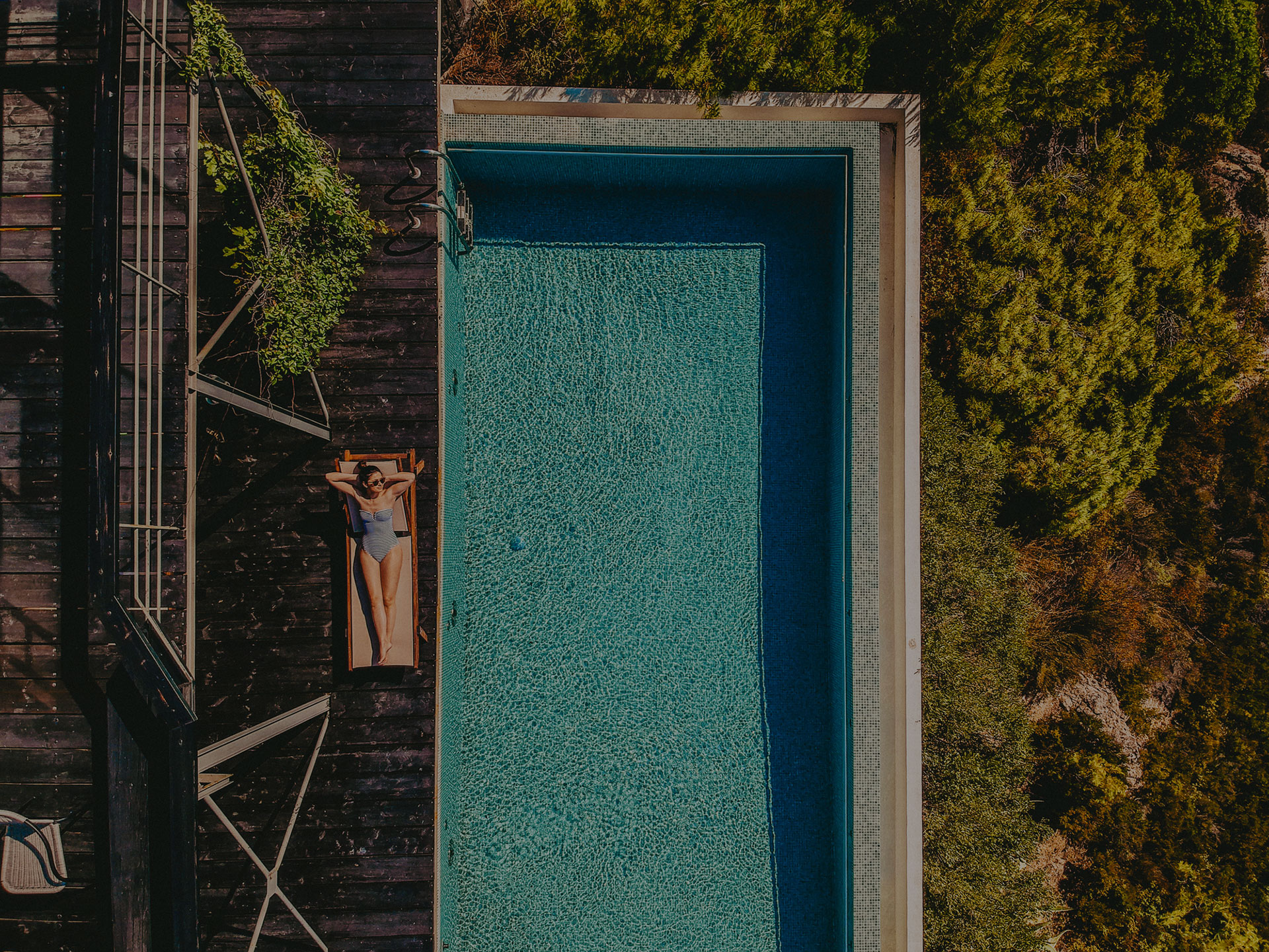 woman sun tanning next to pool
